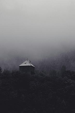 A single house sits atop a forested hill (black & white)