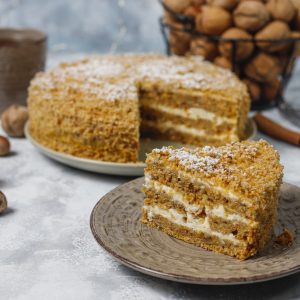 Carrot cake with a slice cut out of it and presented on a smaller plate.